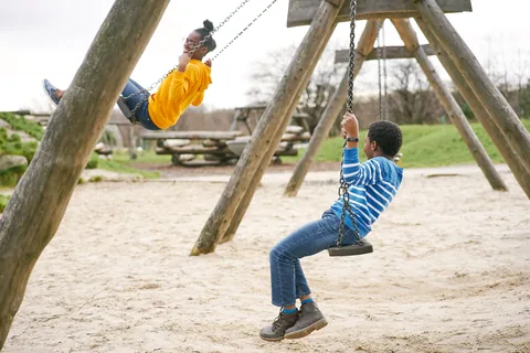 Two children using the adventure-play swings at Cuningar Loop.